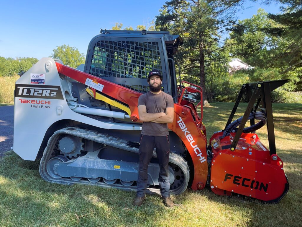 Columbia Land Clearing owner standing in front of skid steer
